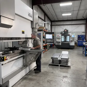 Fabricator reviewing aluminum bending equipment controls