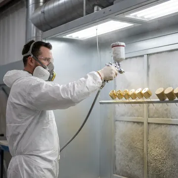UV coating being applied to metal components in industrial finishing facility