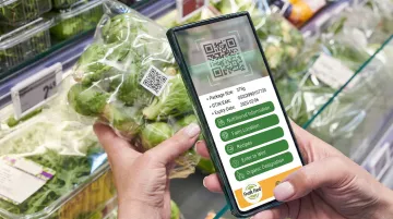 Consumer scanning QR code on food packaging in supermarket aisle