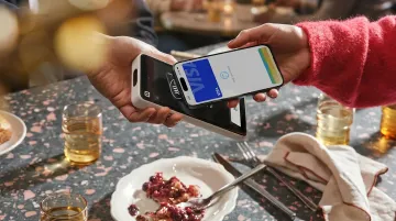 Restaurant server processing contactless digital payment at table with smartphone