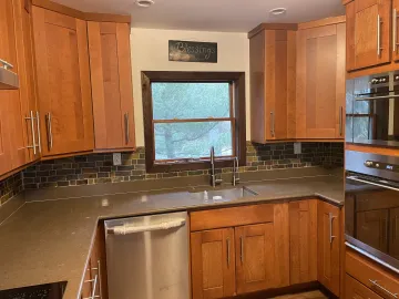 Cabinet maker measuring and installing solid wood white kitchen cabinets in a residential kitchen
