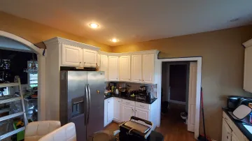 Skilled craftsman measuring and fitting a custom kitchen cabinet