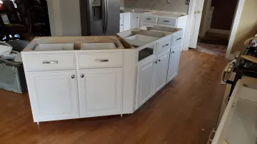 Cabinet craftsman measuring and installing custom kitchen cabinets
