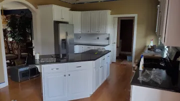 Cabinet maker measuring and installing custom cabinetry in a modern kitchen