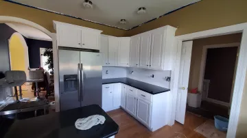 Craftsman measuring and assembling a custom wood kitchen cabinet in a workshop