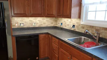 Craftsman installing custom wall mounted kitchen cabinets with precision tools
