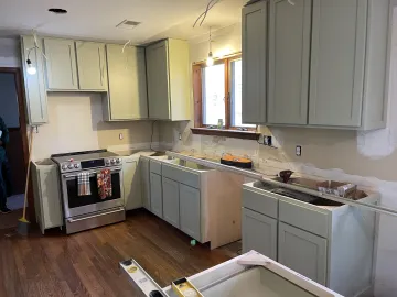 Cabinet maker measuring and installing modern slab kitchen cabinets during a kitchen remodel