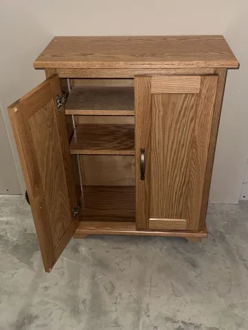 Craftsman measuring and installing a corner linen cabinet in a bathroom