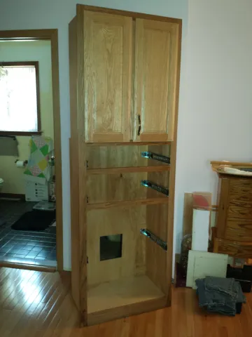 Cabinet maker measuring and installing a custom linen cabinet in a bathroom