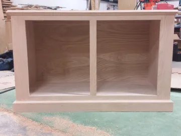 Craftsman applying protective finish to solid wood bathroom cabinet