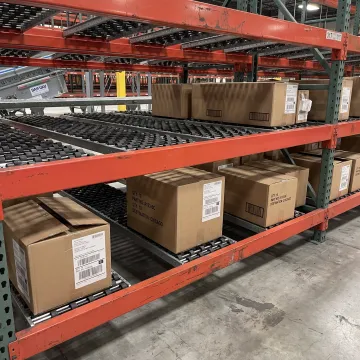 Carton flow rack with roller lanes in warehouse
