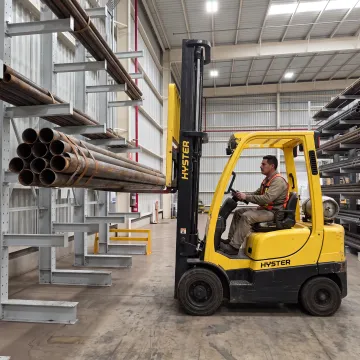 Worker retrieving pipe from cantilever rack