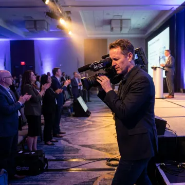 Corporate event photographer and videographer filming a conference
