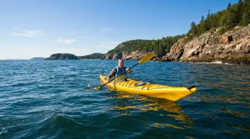 Couple kayaking along rocky Maine coastline near Acadia National Park