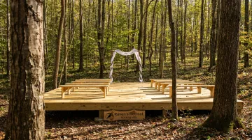 Raven's Retreat Hocking Hills forest ceremony space with rustic arch and guest benches