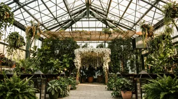 Bohemian botanical garden wedding ceremony outdoor space with greenhouse structures and greenery