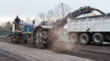 Concrete milling machine grinding damaged highway pavement surface