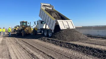 Dump truck delivering asphalt millings to construction site for grading