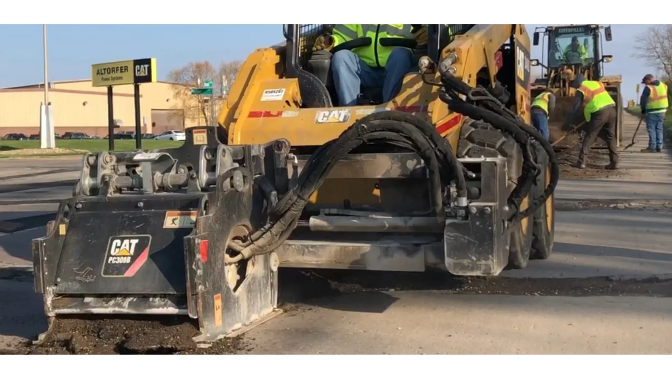 Highway milling machine cutting asphalt surface with traffic control setup