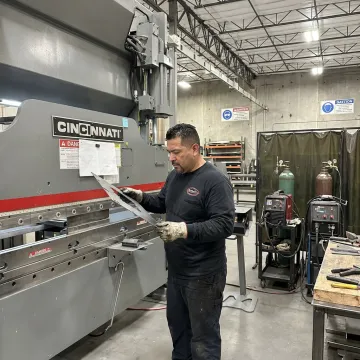 Metal fabricator reviewing parts during production