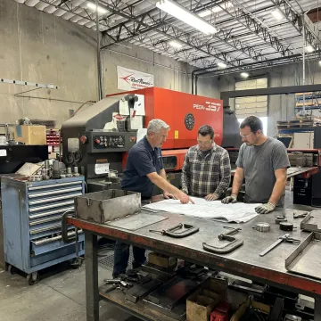 Fabrication team reviewing welded metal assemblies