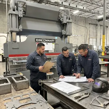 Metal fabrication team reviewing precision part drawings