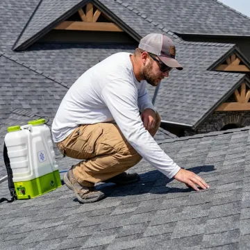 Roof restoration contractor inspecting shingled roof