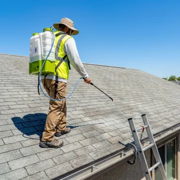 Technician restoring a shingled roof with protective coating