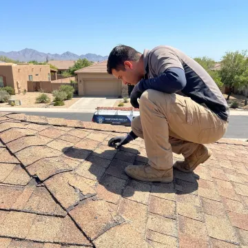 Roof technician inspecting shingles before restoration