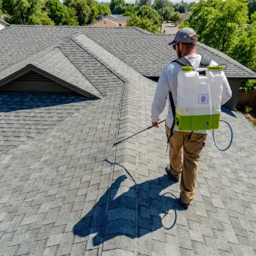 Technician applying asphalt shingle roof coating