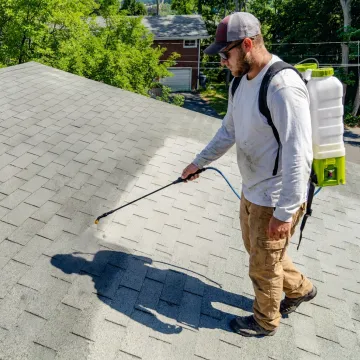 Roof coating technician applying shingle rejuvenation treatment