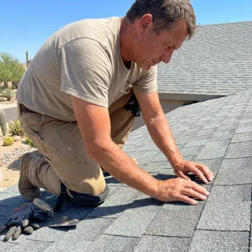 Roofing technician inspecting asphalt shingles