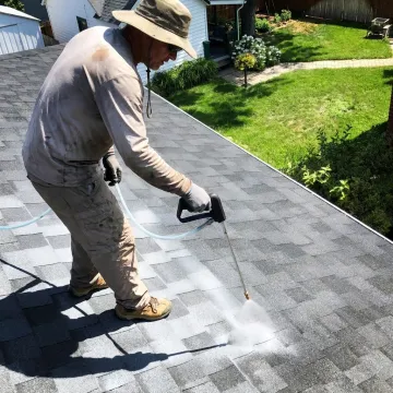 Technician treating an asphalt shingle roof