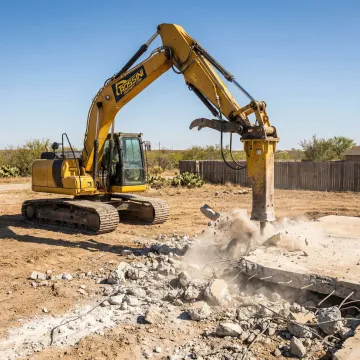 Heavy excavator breaking concrete slab on Denton construction site