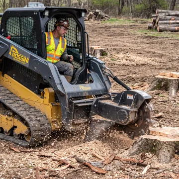 Operator grinding a stump with a skid steer