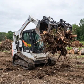 Skid steer using a stump bucket and grapple
