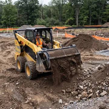 Skid steer screening bucket processing soil