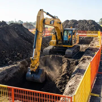 Heavy excavator digging foundation trench on residential construction site