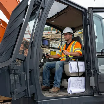 Excavator operator performing precision grading work on a commercial construction site