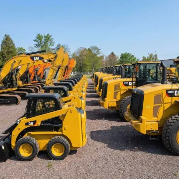 Fleet of construction equipment including excavators and skid steers at Rossini Equipment yard
