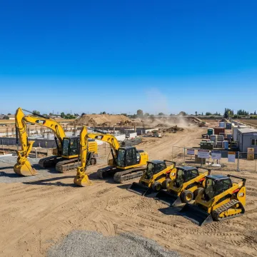 Heavy construction equipment including excavators and skid steers on a Fresno, CA jobsite