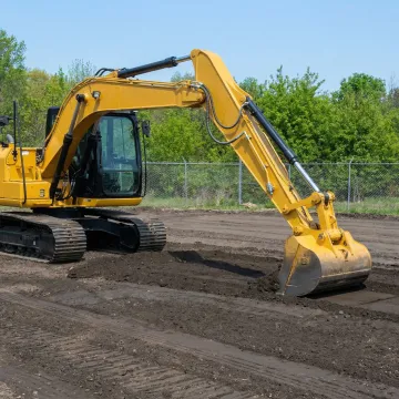 Graded construction site with excavator and operator working on final preparations