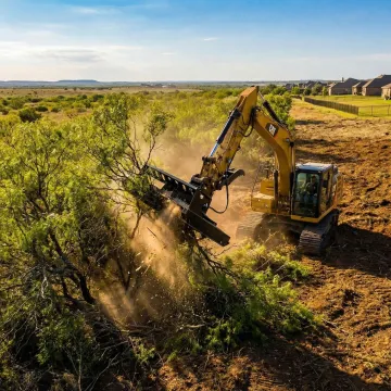 Heavy excavator clearing residential land with trees and brush in Texas