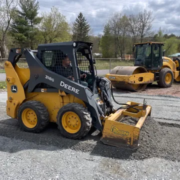 Operator using equipment attachment for roadway work