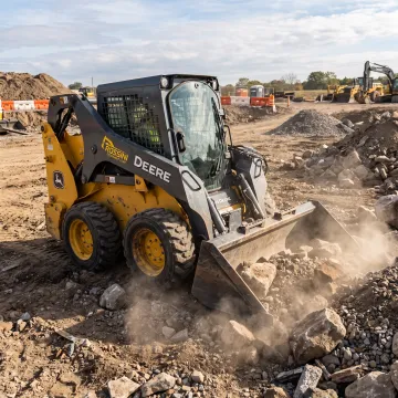 Skid steer using a rock bucket on a jobsite