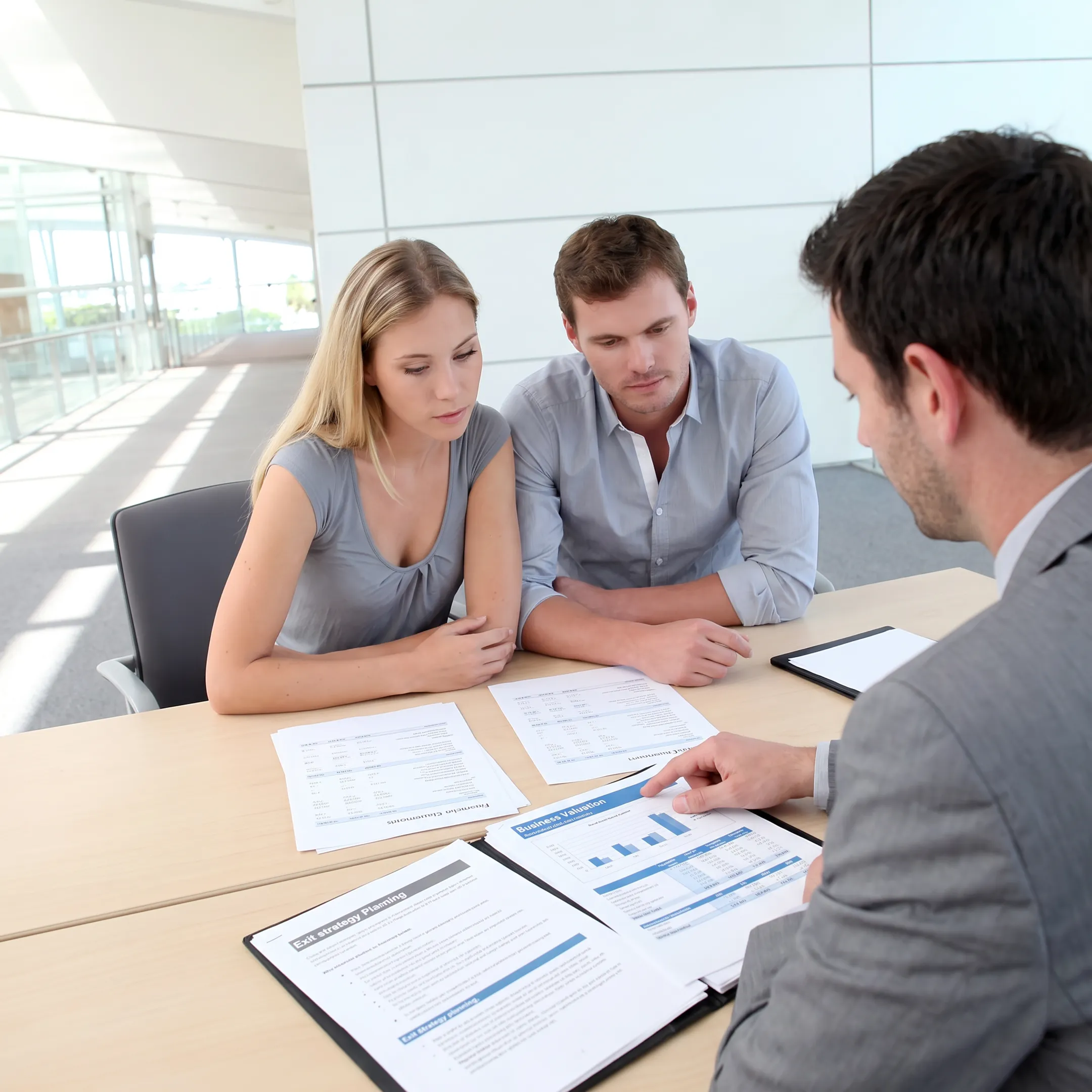 Business advisors reviewing company financial documents with an owner during an exit planning consultation