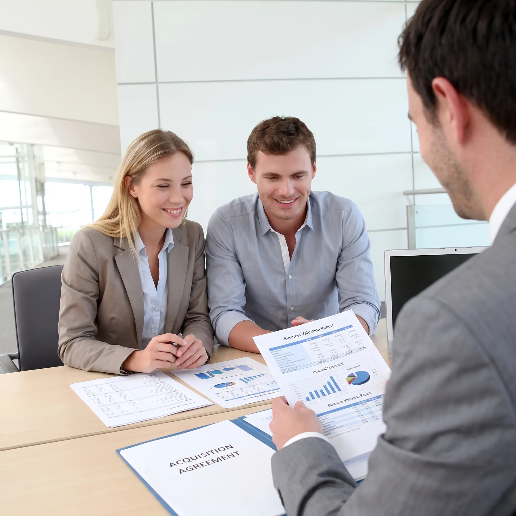 Business advisors reviewing financial documents during a confidential acquisition meeting