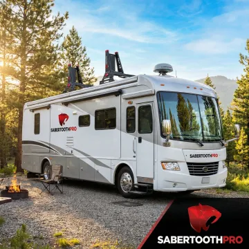 Modern RV with satellite dish and wireless antennas parked at scenic campground with mountain backdrop