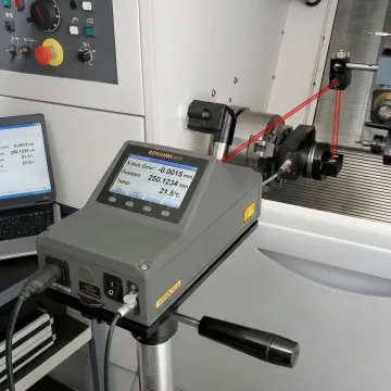 Close-up of precision laser measurement equipment on CNC machine axis