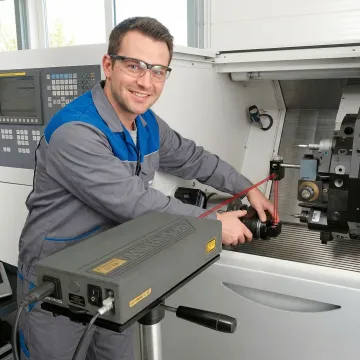 CNC maintenance technician performing precision calibration with laser measurement equipment